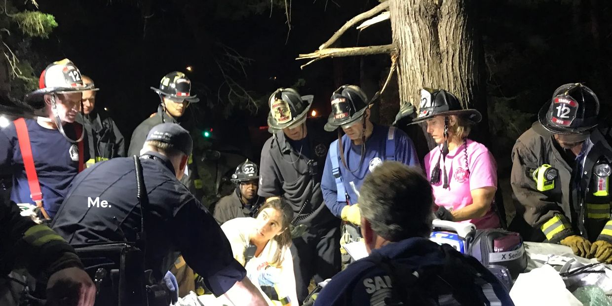 A paramedic hold the hand of a victim entrapped in a car wreck and the firefighters and rescue team create a plan to free him.