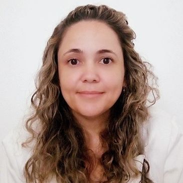 Smiling woman with curly hair against a plain white background.