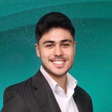 Smiling young man in a suit against a teal background.