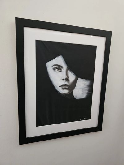 A black and white image of a woman's face within a brushstroke shape