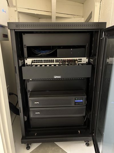 A server rack with network equipment and UPS units inside a room.
