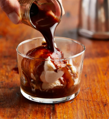 Pouring espresso over vanilla ice cream in a glass for affogato.