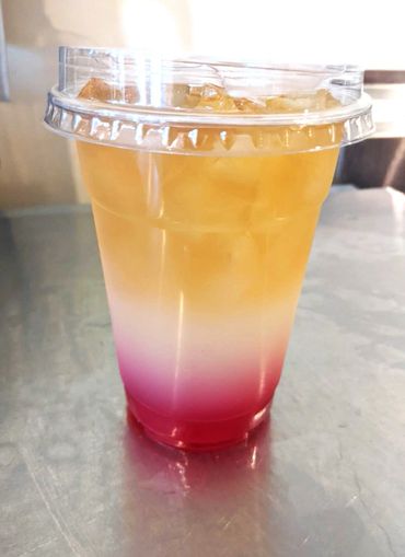 Colorful iced drink with red, white, and orange layers in a plastic cup.