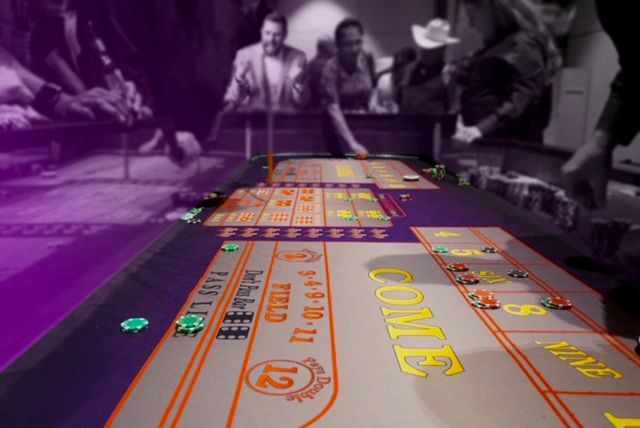 Photo focused on casino craps table with people blurred in background.