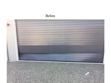 A closed garage door with a dent at the bottom.