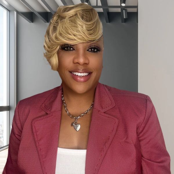 Smiling woman with blond hair and pink blazer.