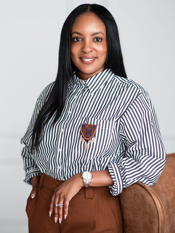 Confident woman in striped shirt and brown pants, smiling warmly.