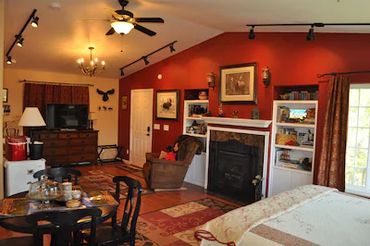 A spacious room with LED TV, a ceiling fan, a table, etc.