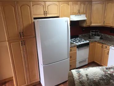 A white refrigerator and wooden cabinets in a kitchen