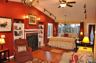 A large bedroom with sofa, chair, fireplace, and more