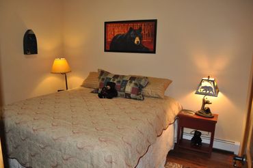 a bed with a teddy bear on it and a painting on the wall