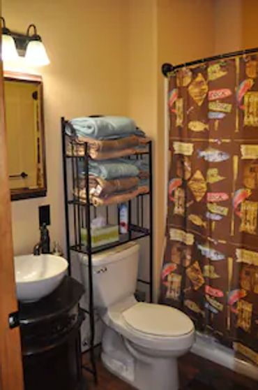 a toilet with a commode, sink, and a rack