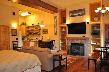 a hall with a LED TV, a bed, and an attached kitchen