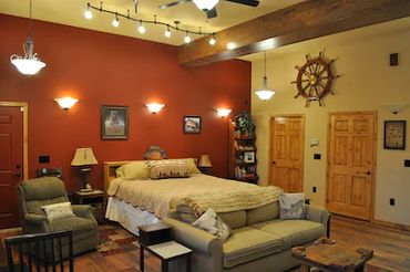 a bedroom with two doors, a bed, a sofa, and more