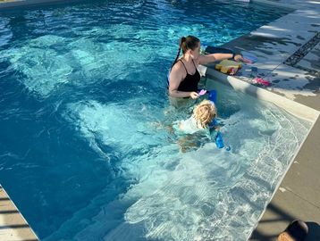 A woman and child playing with pool toys in a swimming pool.