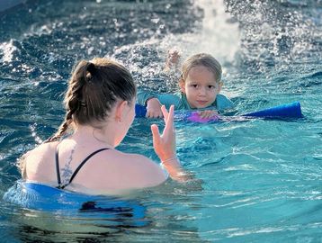 A woman and child enjoying swimming in a pool.