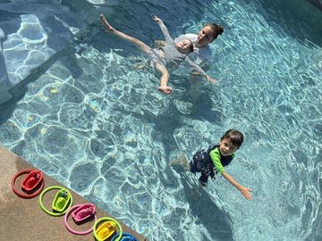 Two children playing in a clear swimming pool on a sunny day.