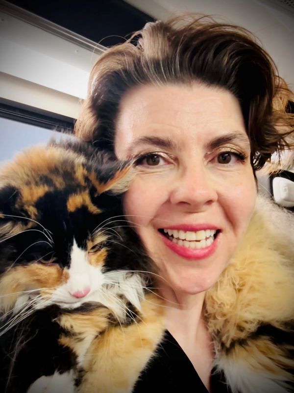 Artana, the owner of Kittington's with a brown cat wrapped around her neck