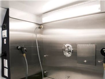 A clean stainless steel industrial wash area with hoses.