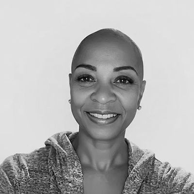 Smiling woman with a shaved head and casual wear.
