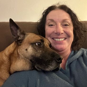 Woman smiling with her dog resting on her shoulder.