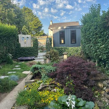 A tranquil backyard garden with lush greenery and a pathway.