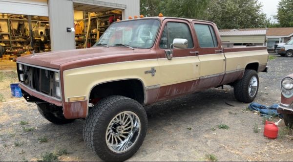Old two-tone Chevrolet Silverado truck with missing front grille.