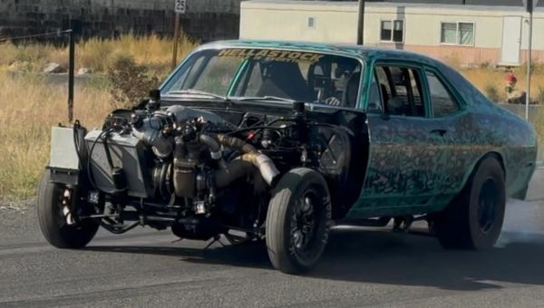 Classic car with its engine exposed, performing a burnout.