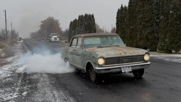 Old car doing a burnout on a wet road.
