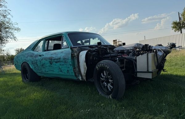A partially restored vintage car without its front fenders.