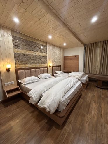 Cozy bedroom with wooden walls and multiple white pillows.