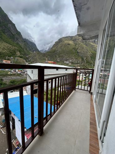 Balcony view of blue rooftops and green mountains under a cloudy sky.