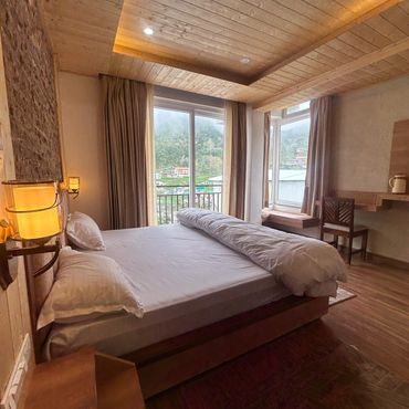 Cozy bedroom with wooden ceiling and large window.