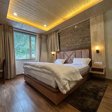 Cozy bedroom with wooden ceiling and large window view.
