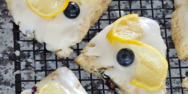 Iced lemon blueberry scones cooling on a rack.