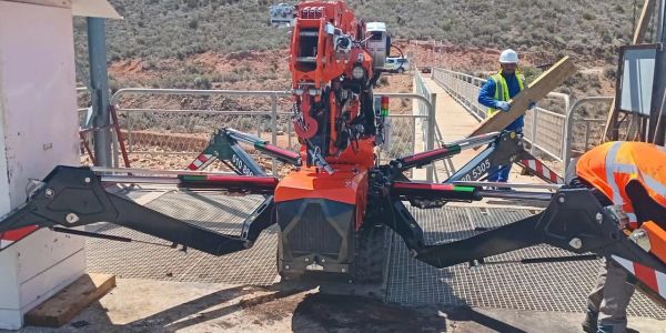 Compact spider crane with extended legs at a construction site.