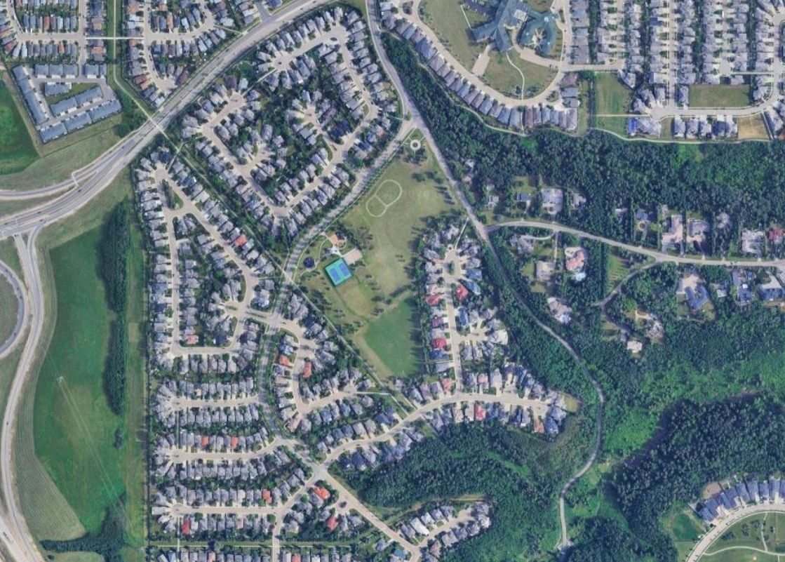 Aerial view of a suburban neighborhood with houses, roads, and green spaces.