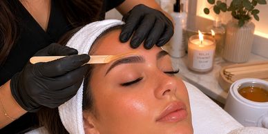 Woman getting eyebrow treatment in a spa setting.
