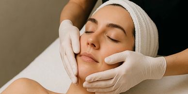 A woman receiving a facial massage with a towel wrapped around her head.