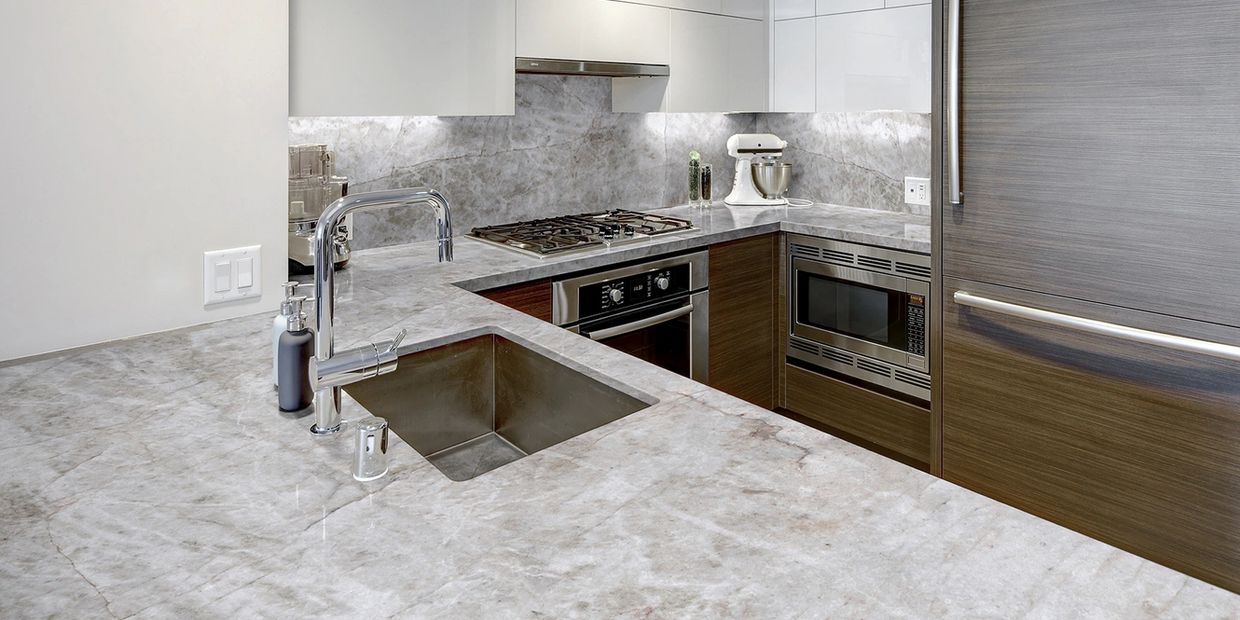Modern kitchen with marble countertops and stainless steel appliances.