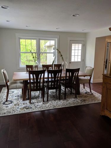 Elegant dining room with wooden table and chairs on a patterned rug.
