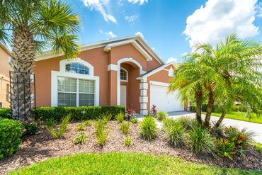 Front of pink house with palm trees and sunny skies