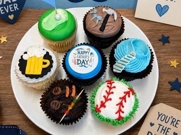 Cupcakes decorated with Father's Day themes including tools, sports, and drinks.