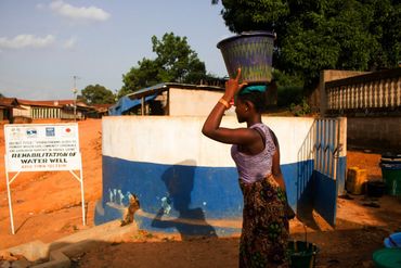 woman collecting clean water from a well installed through aqua harvest