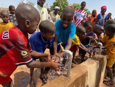 children washing hands at a clean water point provided through aqua harvest