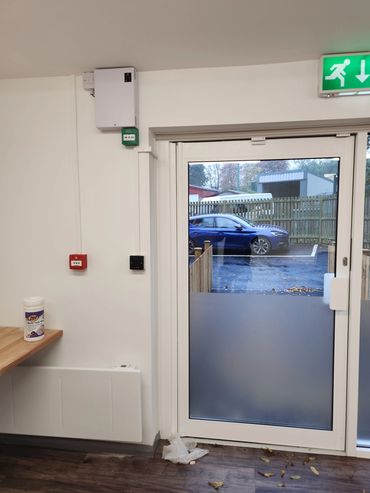 Indoor view of a glass door leading outside to a parking lot with a blue car.