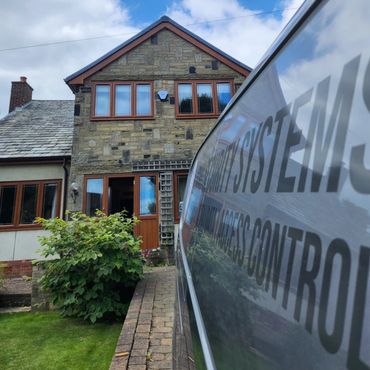 Stone house with wooden windows and a security van in front.