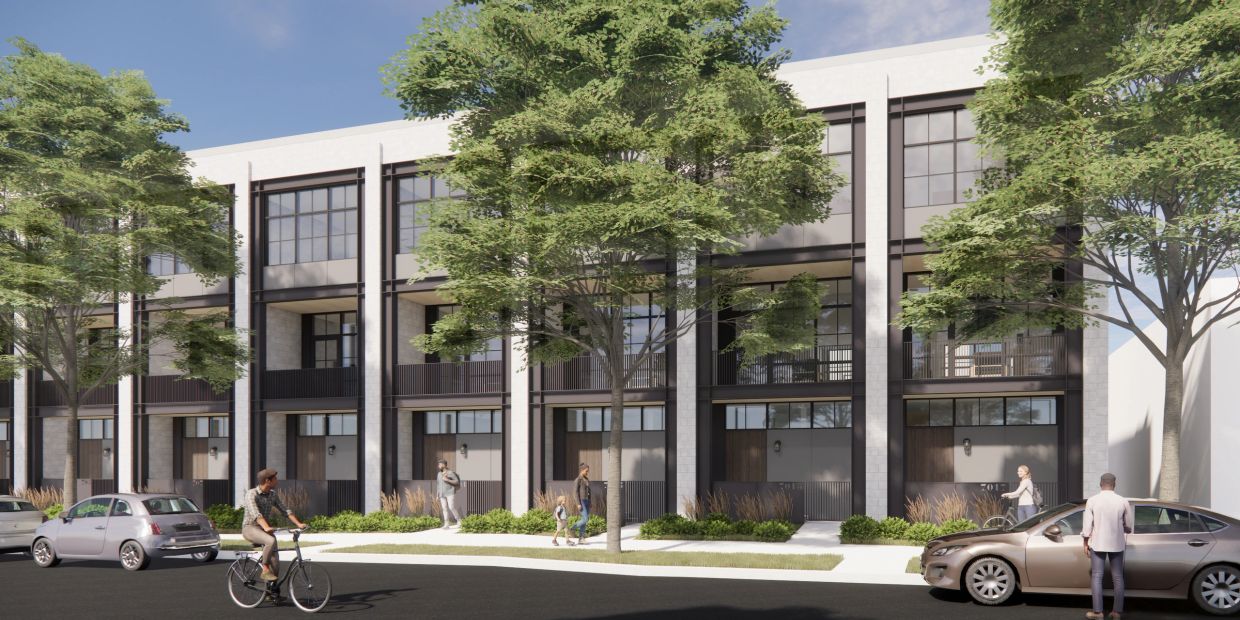Modern townhouses with people and cars on a sunny day.