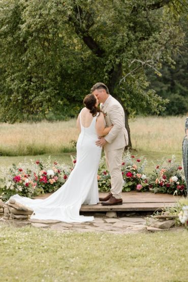 Bride and groom kissing at outdoor wedding ceremony.