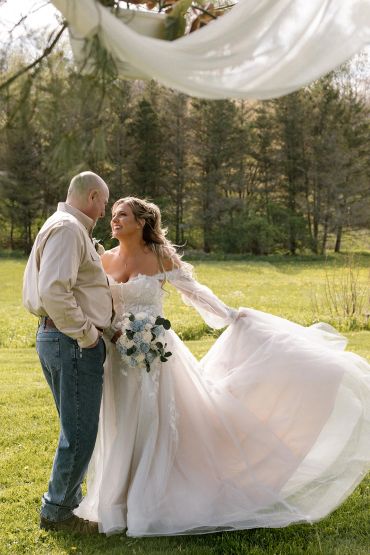 Bride and man sharing a joyful moment outdoors.
